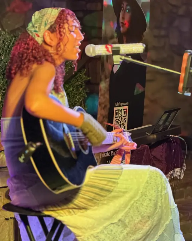 Singer with an acoustic guitar performing a seated set at the open mic