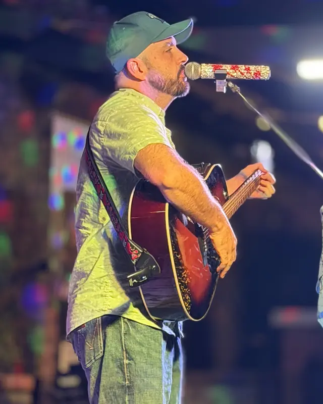 Guitarist singing under the stage lights at the open mic
