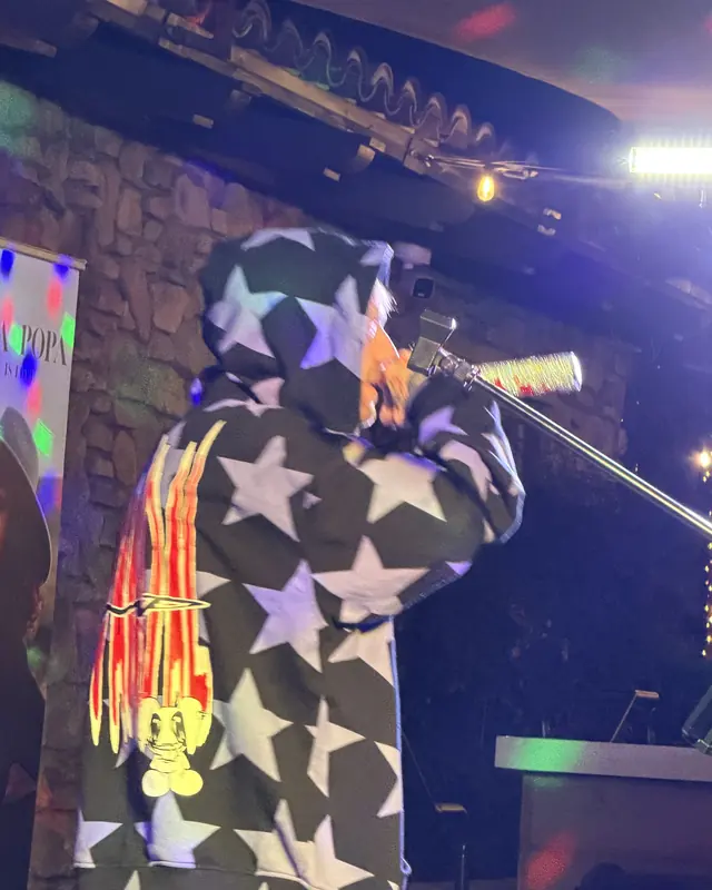 Performer in a star-print jacket singing at the open mic
